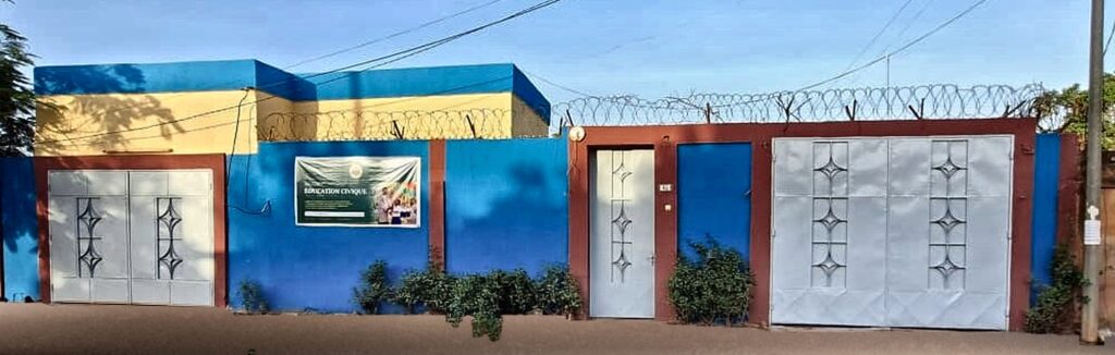 Façade de nos locaux à Boulmiougou, Ouagadougou : bâtiment bleu et jaune, portail, porte d'entrée et grand portail gris